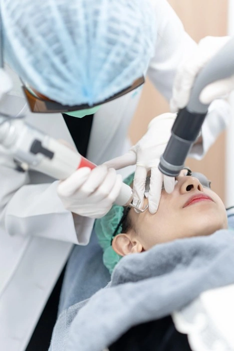 Dermatologist in full protective gear performing a professional laser skin treatment on a woman at an aesthetic clinic