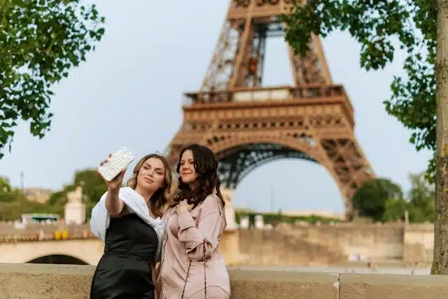 Two women taking a selfie in front of the Eiffel Tower during a guided tour in Paris, France