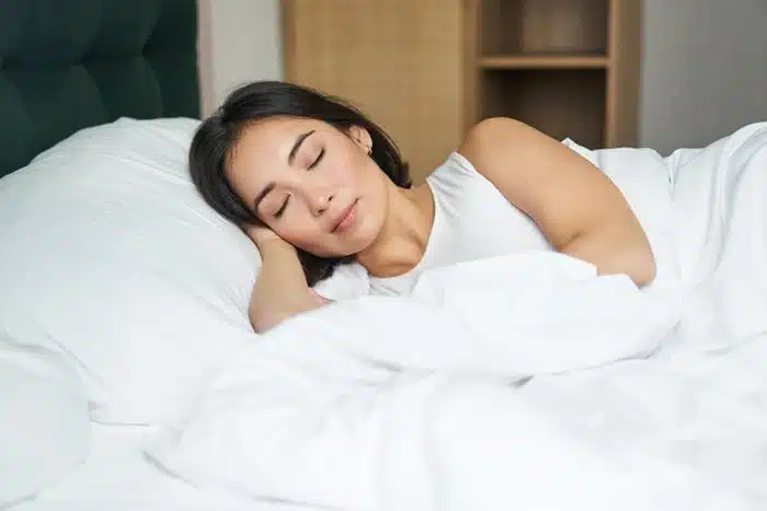 a woman sleeping peacefully in a hotel bed for quality rest while traveling