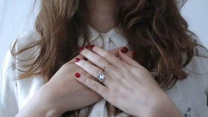 Woman with hands crossed over her chest, practicing self compassion during a difficult season
