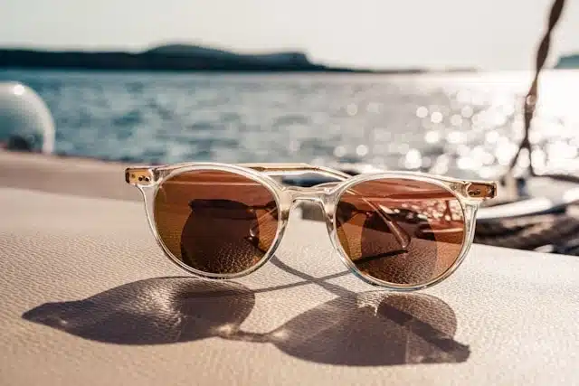 Clear-framed sunglasses with tinted lenses on a boat near the water