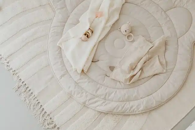 Neutral-toned organic baby essentials laid out on a soft bear-shaped mat
