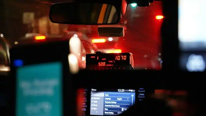 A glowing taximeter displaying a fare inside a cab at night, a reminder to always check the meter is running to avoid being overcharged as a tourist.