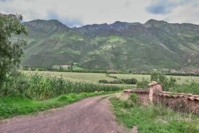 Dirt trail near Lamay winding through farmland with Andes mountains in the background