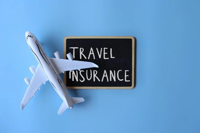 A miniature airplane next to a chalkboard sign reading Travel Insurance, symbolizing the importance and benefits of having proper coverage when flying abroad