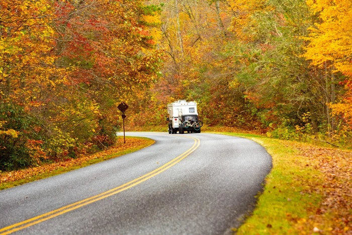 RV camper driving along a scenic Virginia road lined with fall foliage