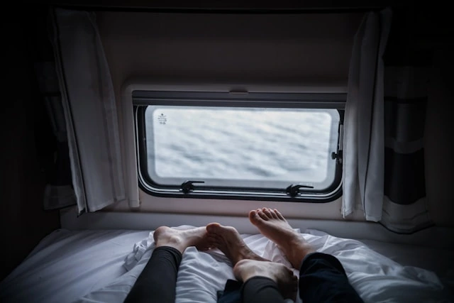 Two travelers relaxing barefoot on an RV bed, one of the simple benefits of watching the water roll by