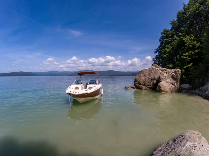 Boat anchored near a rocky shoreline on Lake Jocassee, a popular boating and kayaking spot in the South Carolina Upstate