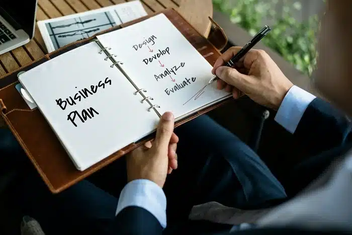 Entrepreneur writing a business plan with design, develop, analyze, and evaluate steps