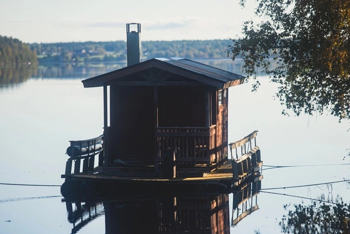 Traditional wooden floating sauna boat on a calm Finnish lake in Lapland