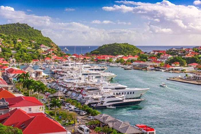 Aerial view of Gustavia harbor in St Barts, lined with luxury yachts and red-roofed villas