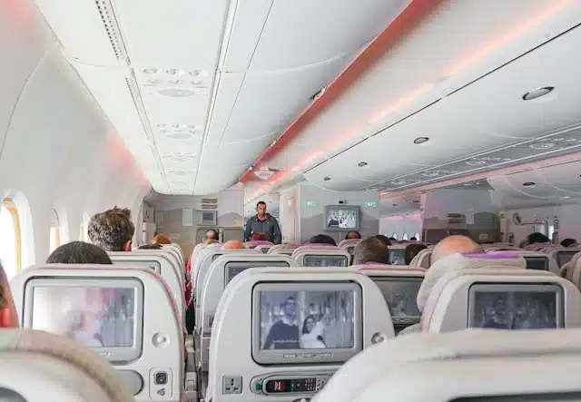 Passengers watching in-flight entertainment screens throughout a full plane cabin