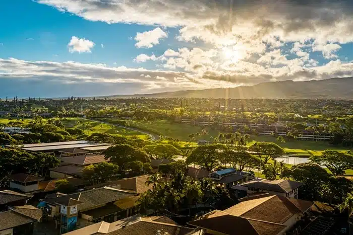Sunset view over a residential area in Maui, Hawaii, with lush greenery and mountains