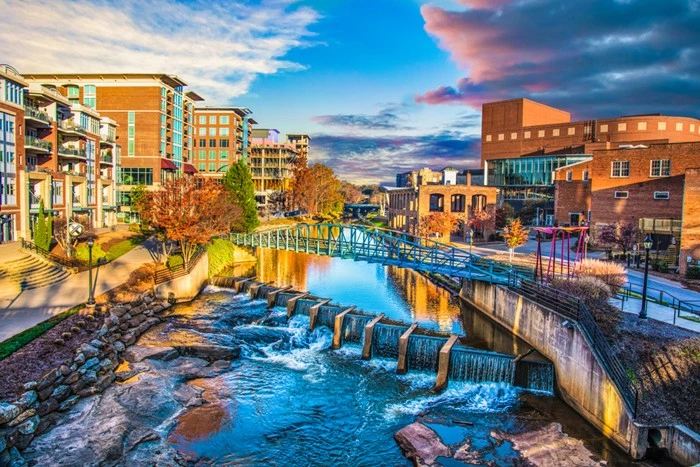 Outdoor things to do in Greenville, SC include walking along the Reedy River past downtown's small falls and pedestrian bridge at sunset