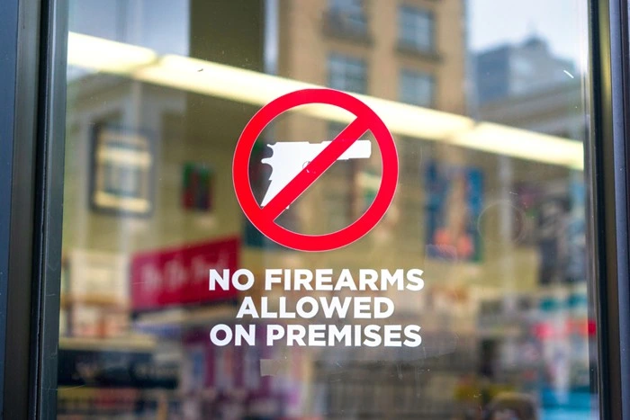 A storefront window sign reading 'No Firearms Allowed on Premises,' marking a restricted concealed carry location