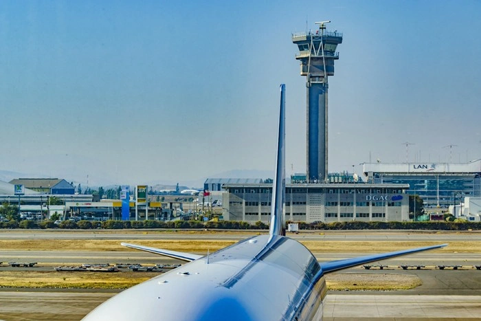 Airplane wing on the tarmac at Santiago International Airport with the control tower in the background