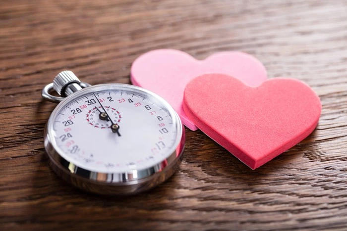 Stopwatch and heart cutouts symbolizing timed dating rounds