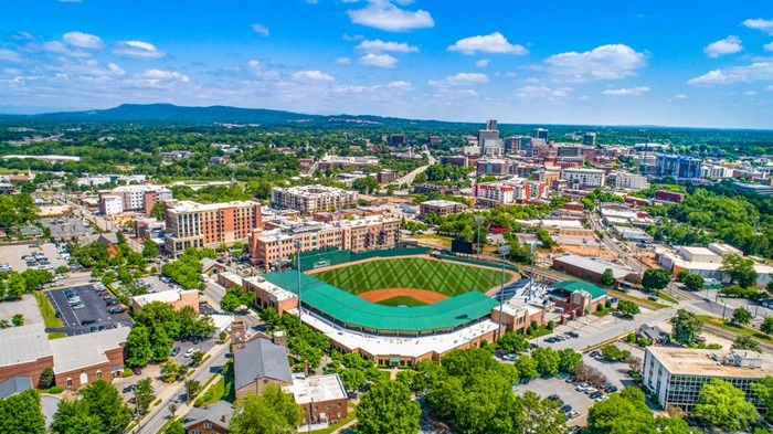 Aerial view of downtown Greenville, South Carolina, with the baseball stadium, city skyline, and Blue Ridge foothills in the distance