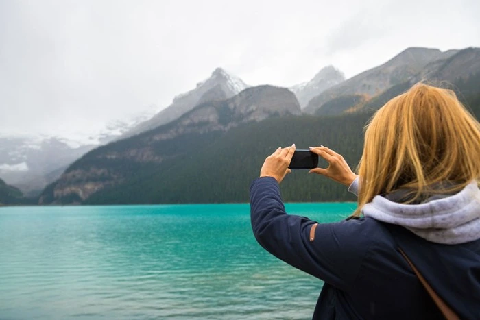 Tourist taking photo with phone at Banff National Park with turquoise lake and mountains