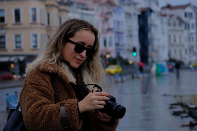 Content creator adjusting her camera settings on a rainy city street