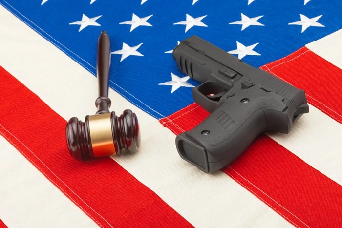 A gavel and handgun resting on an American flag, symbolizing the legal side of traveling with a concealed carry permit in USA