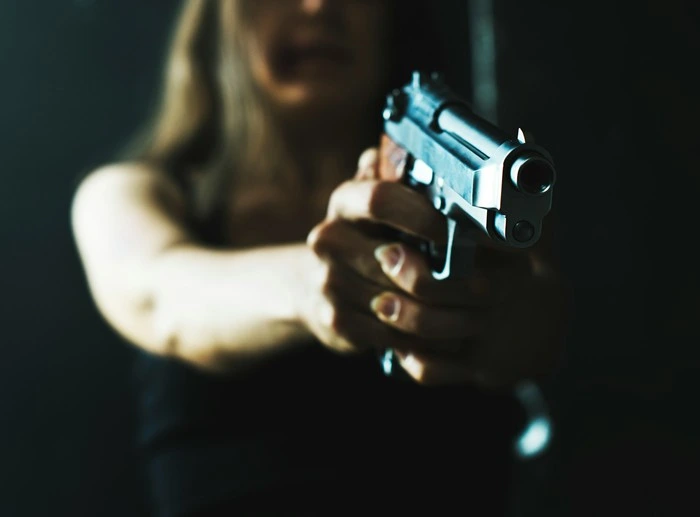 A woman aiming a handgun with both hands, representing confidence and preparedness for concealed carry permit holders