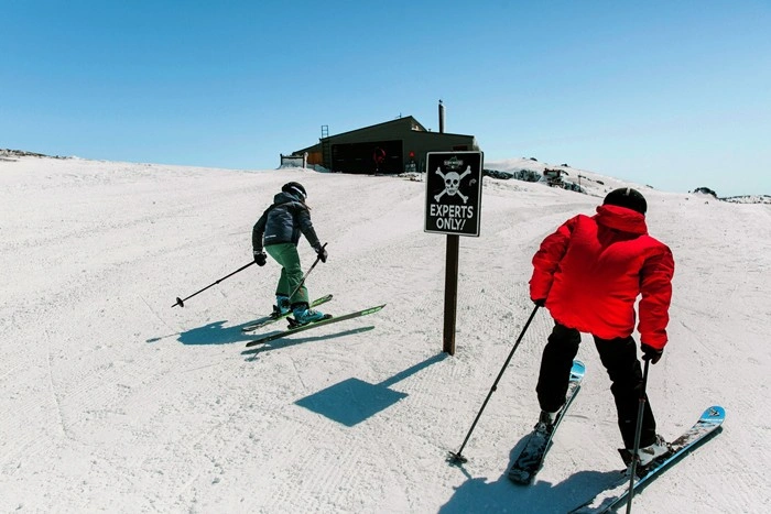 Skiers passing an "Experts Only" sign at Kirkwood Resort's expert terrain zone