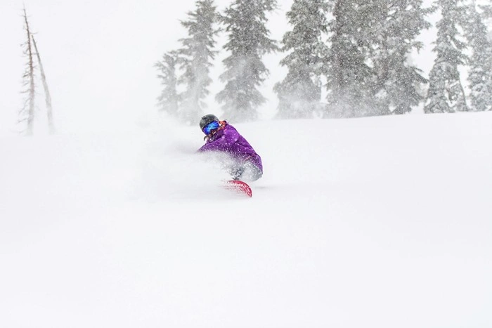 Snowboarder carving through fresh powder during a snowstorm at Kirkwood Ski Resort, California