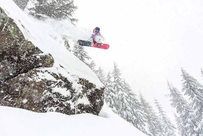 Snowboarder catching air off a rocky cliff drop at Kirkwood Ski Resort