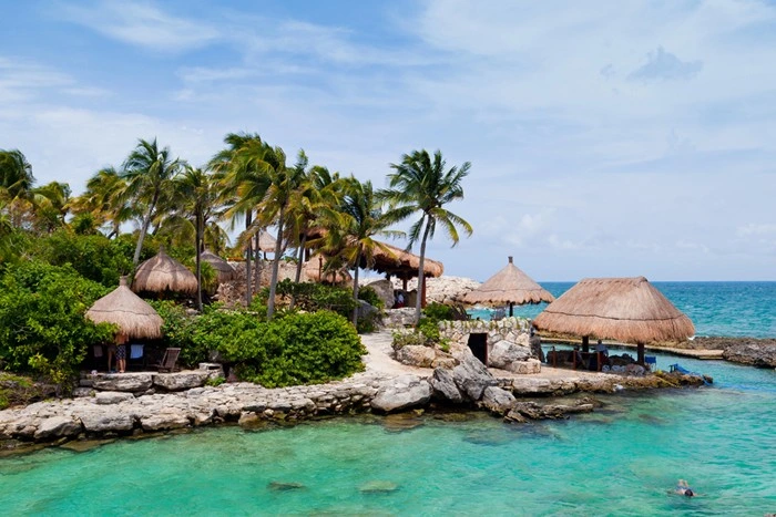 All-inclusive resort in Cancun, Mexico with thatched-roof palapas along a rocky Caribbean shoreline