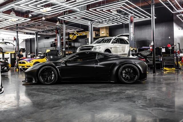 Matte black wrapped sports car parked inside a Dubai vehicle customization garage