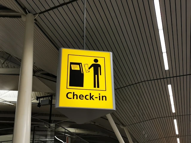Airport check-in sign reminding travelers to confirm baggage policy before their flight