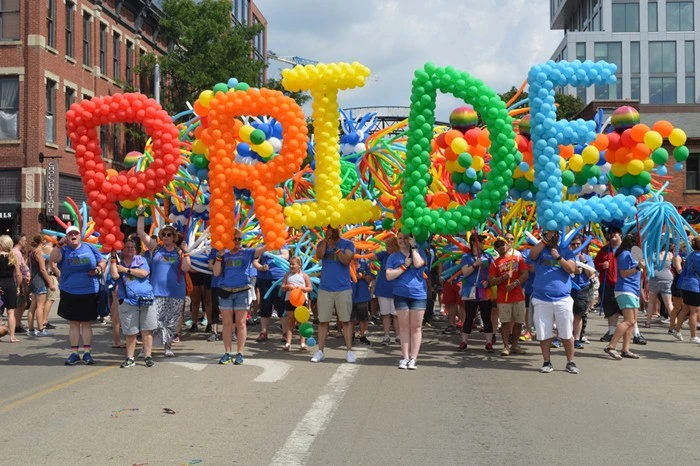 Columbus Pride festival parade with colorful balloon displays and crowds celebrating in a downtown street.