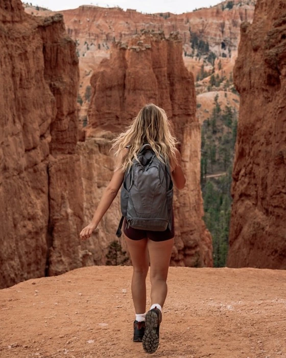 Woman hiking solo through red rock canyon trail with backpack, comfort for solo adventures abroad