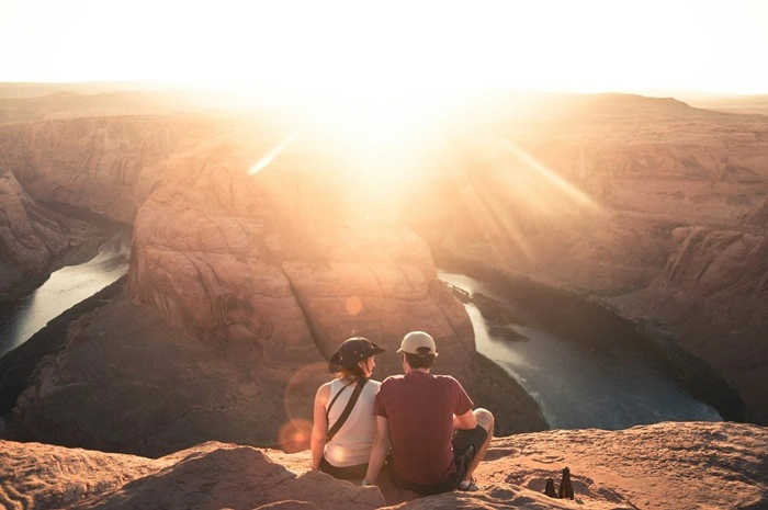 Couple sitting together at sunset overlooking a canyon on a hiking getaway