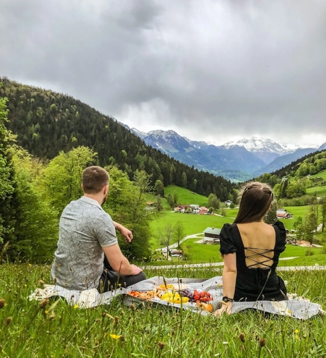 Couple enjoying a romantic picnic overlooking green mountain valley