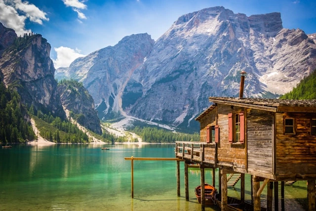 Wooden lakeside cabin in the Dolomites with turquoise water and mountain backdrop, perfect for a digital detox adventure