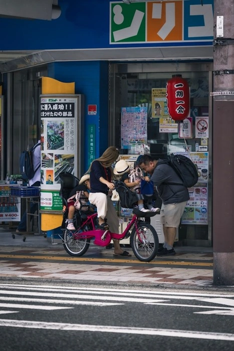 Family with a child seated in a bike seat outside a storefront in Japan