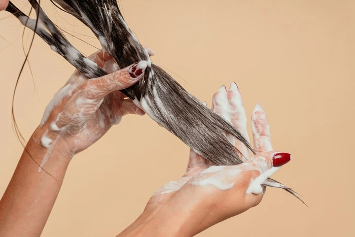 Close-up of hands shampooing hair, a common trigger point for noticing hair loss