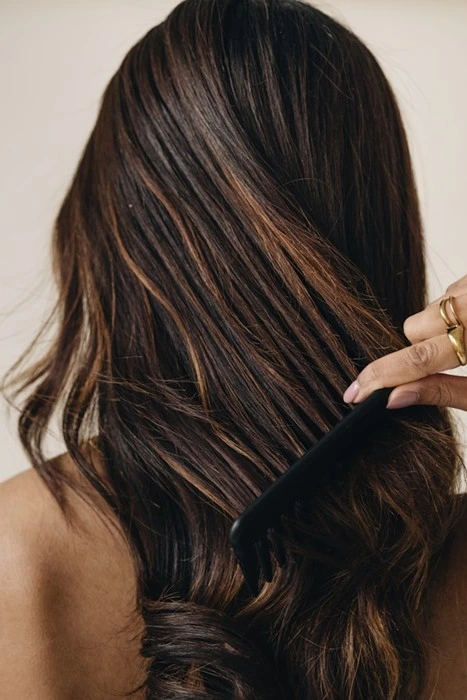 Woman combing through thick, healthy hair, the kind of result restoration aims to achieve