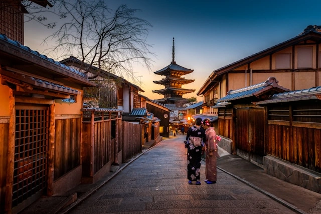 Historic Kyoto street at dusk with traditional architecture and pagoda in view