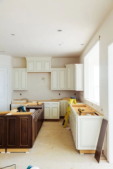 Kitchen remodeling tips in action: cream cabinetry installed mid-renovation with tools and ladder on site