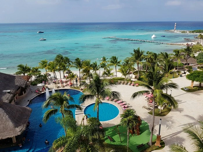 Luxury tourism in Cancun for senior travelers featuring an oceanfront resort with pools, palm trees, and turquoise Caribbean waters