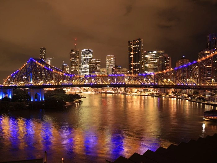 Luxury travel in Brisbane: Story Bridge and city skyline lit up at night reflecting on the river