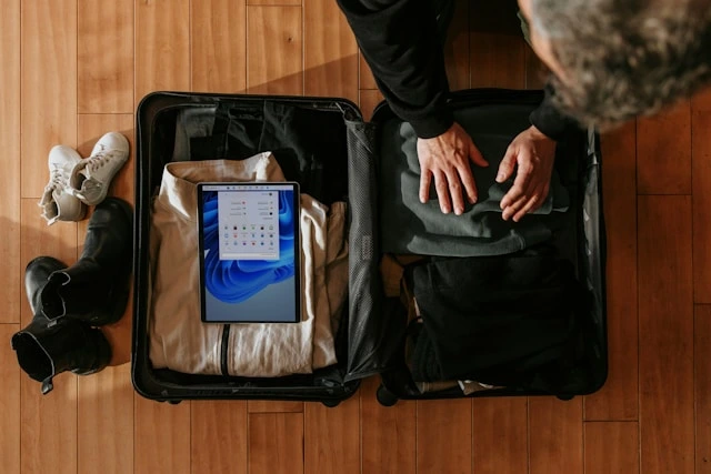 Man packing versatile travel wardrobe essentials into a suitcase, including neutral clothing and shoes
