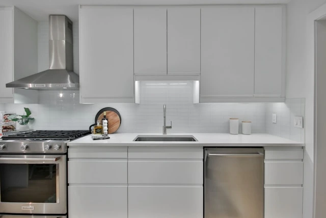 Modern white kitchen with stainless steel appliances, gas range, and tiled backsplash