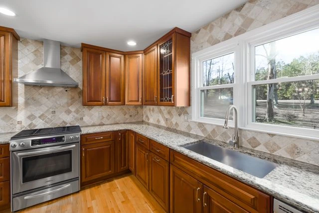 Wood kitchen remodel with granite countertops, tile backsplash, and window over the sink