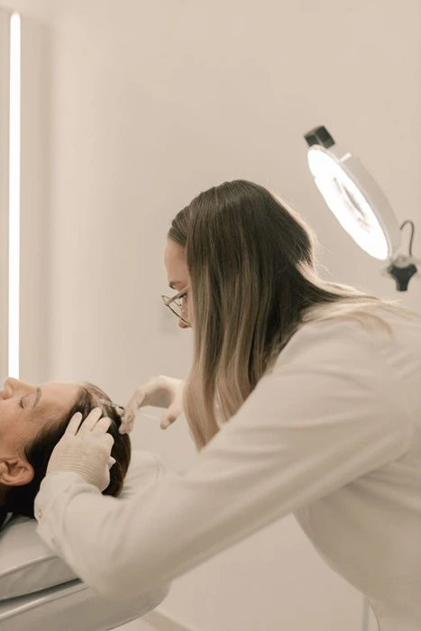 Specialist examining a patient's scalp during a non-surgical hair restoration consultation