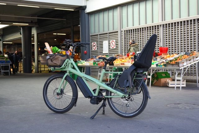 Passenger seat for e-bike installed on a green cargo e-bike parked at an outdoor market