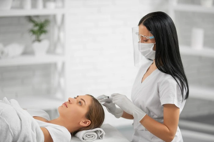 Provider in protective gear performing a scalp procedure during a hair transplant session